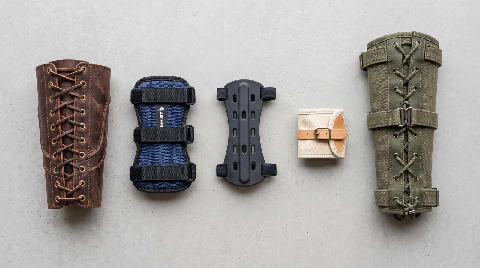 Five types of archery arm guards side by side: leather bracer, nylon ballistic, EVA foam, short wrist guard, and full-arm bracer